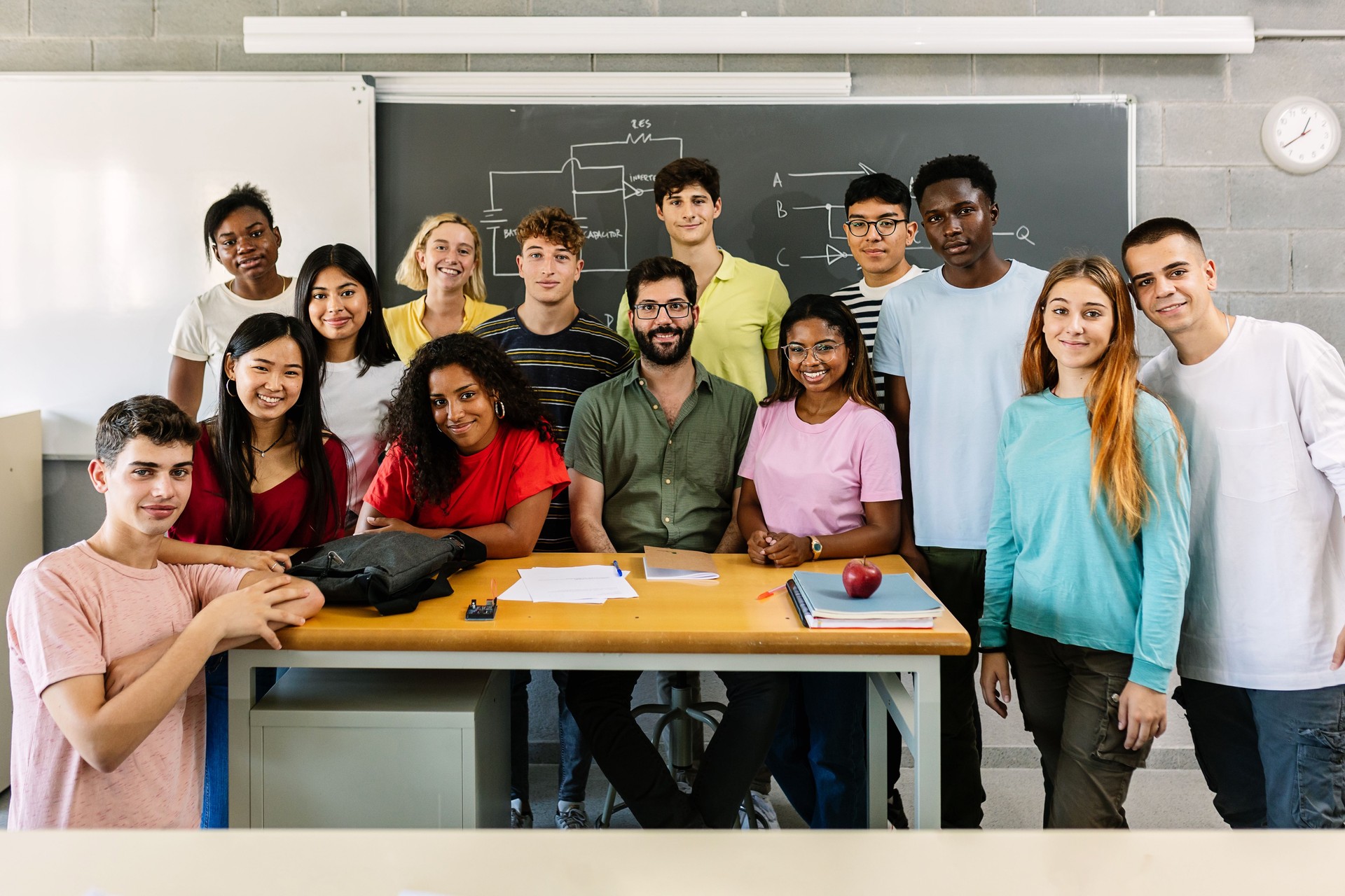 Large group portrait of millennial students with male teacher in classroom